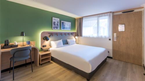 a bedroom with a white bed and a desk and a chair at Campanile NATURE - Lyon Est Bron Eurexpo in Bron