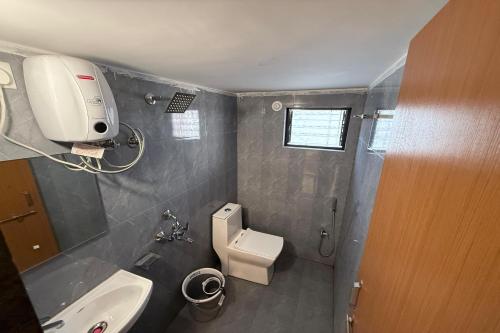 a small bathroom with a toilet and a sink at Indraprastha Executive Lodging in Pune
