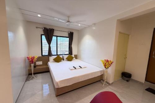a bedroom with a bed and a window and flowers at Indraprastha Executive Lodging in Pune