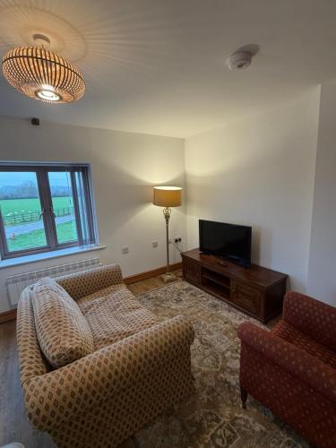 a living room with a couch and a television at Flat 2, Coneygre Farm in Hoveringham