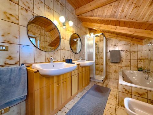 a bathroom with two sinks and a mirror and a tub at Belvedere Solferino panoramic view in Campolongo