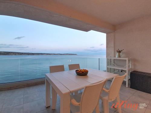 a dining room with a table and a view of the ocean at Seafront Apt Mellieha with Stunning Sea Views in Is-Sellum