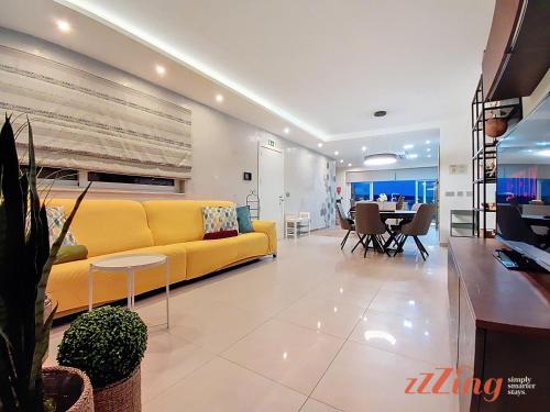 a living room with a yellow couch and a table at Seafront Apt Mellieha with Stunning Sea Views in Is-Sellum