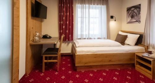 a bedroom with a bed and a desk and a window at Einzelzimmer 13 in Heidenheim