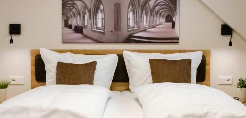 a bed with white pillows and a picture on the wall at Doppelzimmer 14 in Heidenheim