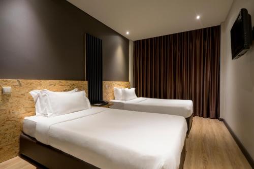 a hotel room with two beds and a television at HF Ala Sul in Porto
