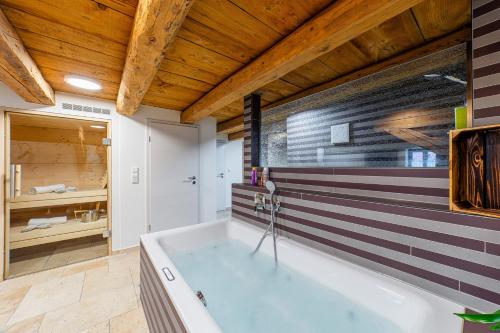 a bath tub in a bathroom with a wooden ceiling at Wellness Apartment Suite "Paradies Suite" in Spalt