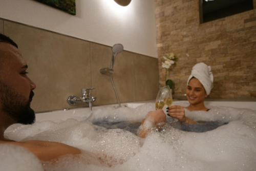 a man and woman sitting in a bath tub with a glass of wine at Wellness Suite - Dream SPA in Spalt