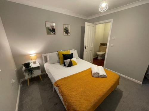 a bedroom with a bed with a yellow blanket on it at Thornaby Lodge in Thornaby on Tees