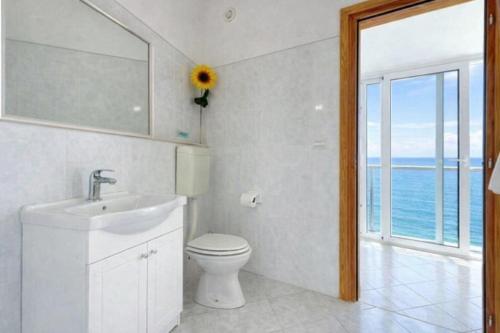 a bathroom with a sink and a toilet and a window at Family home away on the beach, free parking at the house in Marusici 