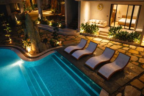 a swimming pool with lounge chairs next to a house at Bella Vida Resort, Uluwatu in Uluwatu