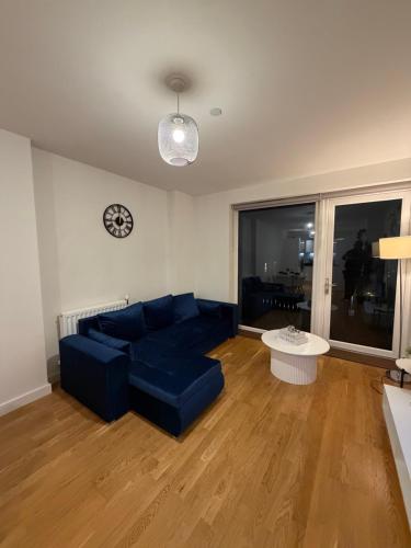 a living room with a blue couch and a table at Prestige London Apartment Balcony Views in London