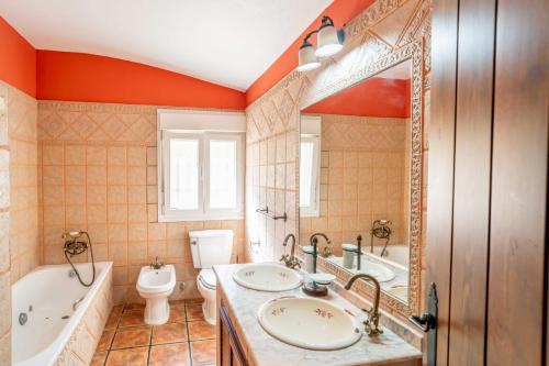 a bathroom with two sinks and a tub and a toilet at El Acebuchal de Ubrique in Ubrique