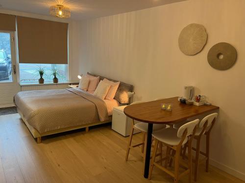 a bedroom with a bed and a table and a table and chairs at Quarles 80 - free parking in Noordwijk aan Zee