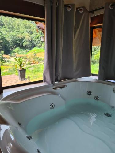 a bath tub sitting in front of a window at Chalé 2 com hidromassagem in Camanducaia