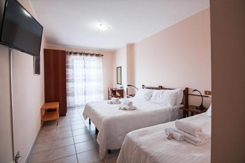 a hotel room with two beds and a flat screen tv at Albergo Parco Gran Sasso in Castel del Monte