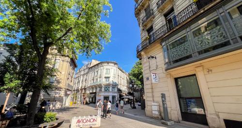a city street with buildings and people walking on the sidewalk at Duplex moderne au Palais des Papes in Avignon