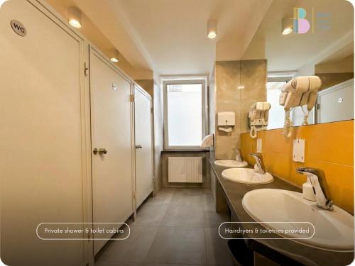 a bathroom with two sinks and two mirrors at Bello ApartHostel Private Rooms in Warsaw