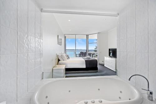 a bathroom with a tub and a bedroom with a bed at Sandcastle Apartments in Port Macquarie