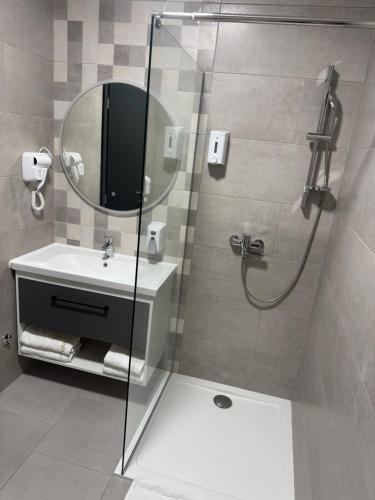 a bathroom with a shower and a sink and a mirror at Pansion Afitos in Laktaši