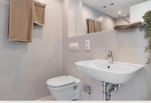 a white bathroom with a sink and a toilet at Dom Central Suite in Greifswald
