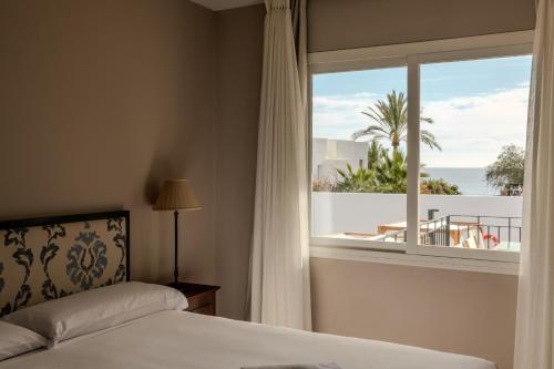 a bedroom with a bed and a window with a view of the ocean at Siete Villas Olivencia Natural in Agua Amarga