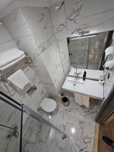 a white bathroom with a sink and a toilet at Akgül Otel in Malatya