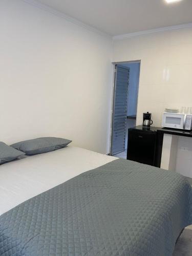 a bedroom with a bed and a microwave on a counter at Pousada Pazzini in Guarujá