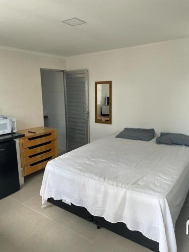 a bedroom with a large white bed and a dresser at Pousada Pazzini in Guarujá