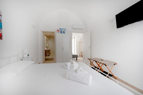 a white bedroom with a bed with towels on it at Ranieri rooms & relax stella in Mola di Bari