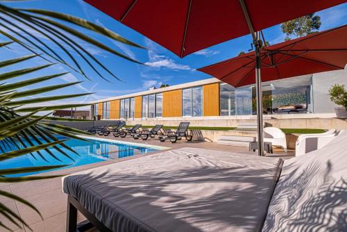 a pool with a bed and umbrellas next to a building at "Villa Carpe Diem" Country house in Cambarinho