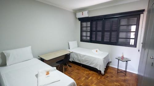 a small room with two beds and a window at Jahu Center Lodge in Jaú