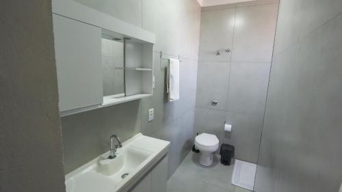 a white bathroom with a sink and a toilet at Jahu Center Lodge in Jaú