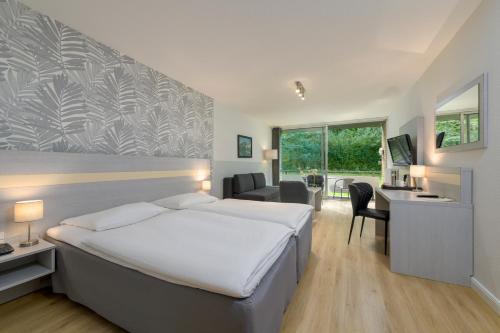 a hotel room with a large bed and a desk at Sunday Hotel des Nordens in Flensburg