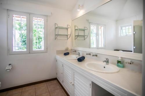 a white bathroom with a sink and a mirror at Beach, Blue Sea, Sunset and Private Pool in Rivière Noire