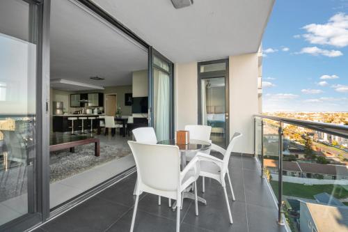 a dining room with a table and chairs on a balcony at Aquarius Luxury Suites in Bloubergstrand