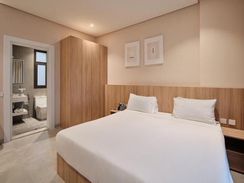 a bedroom with a large white bed and a bathroom at The Code Residence - ذا كود ريزيدنس in Kuwait