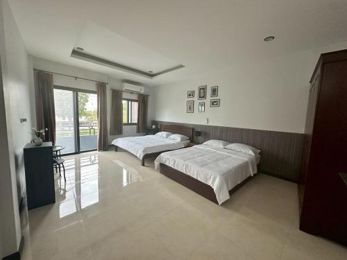 a bedroom with two beds and a window at Cocoon Casa in Hat Yai