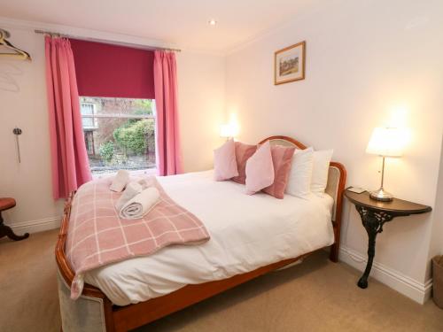 a bedroom with a bed with pink curtains and a window at Kirkham House in Matlock