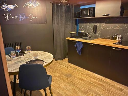 a kitchen with a table and a counter with wine glasses at Suite Casanova avec SPA & Escape Love Game - Doux Bleu Jeux in Niort