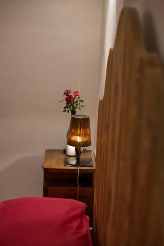 a table with a lamp and a vase of flowers on it at Palazzo Tronconi agriturismo in Arce