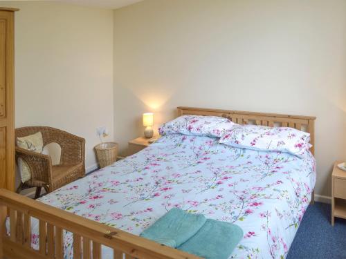 a bedroom with a bed with a floral bedspread at Heather Brae Lodge in Nancledra