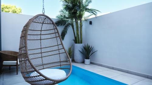 a rattan chair hanging over a swimming pool at Maison le patio in Saint-Denis