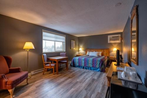 a hotel room with a bed and a desk and a table at Days Inn by Wyndham Burns in Burns