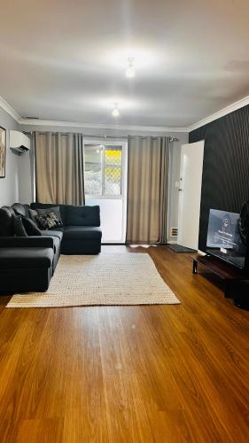 a living room with a black couch and wooden floors at Perth Airport 2 Bedroom duplex unit not apartment in Perth
