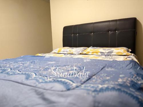 a bed with a blue blanket on top of it at Sri Nabalu Apartment Platinum Putatan in Kota Kinabalu