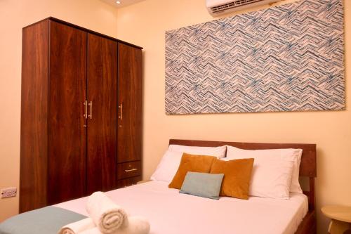 a bedroom with a bed with a wooden cabinet at Oasis Guesthouse Juba in Juba