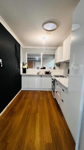 a kitchen with white cabinets and a wooden floor at Perth Airport 2 Bedroom duplex unit not apartment in Perth