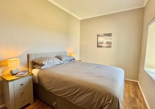 a small bedroom with a bed and a nightstand with two lamps at Sunset Cottage in Llanddulas