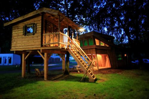 a tree house with a slide in the grass at Wooden Lodge Victor de Vos I Slapen in een echte boomhut in Rijen